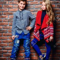 72901028-kid-s-fashion-modern-nine-year-old-boy-and-a-girl-posing-at-studio-over-brick-wall-background